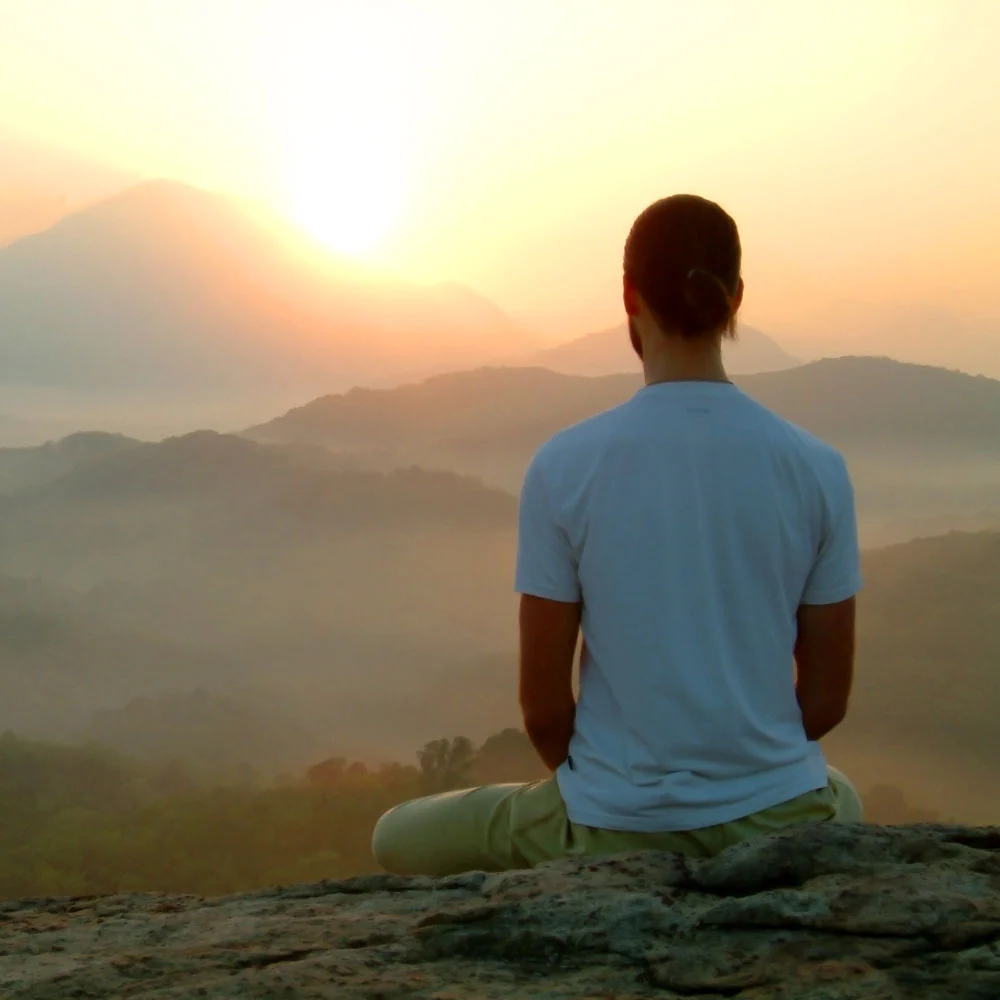first light living hero image, man meditating on top of a mountain, watching the sunrise